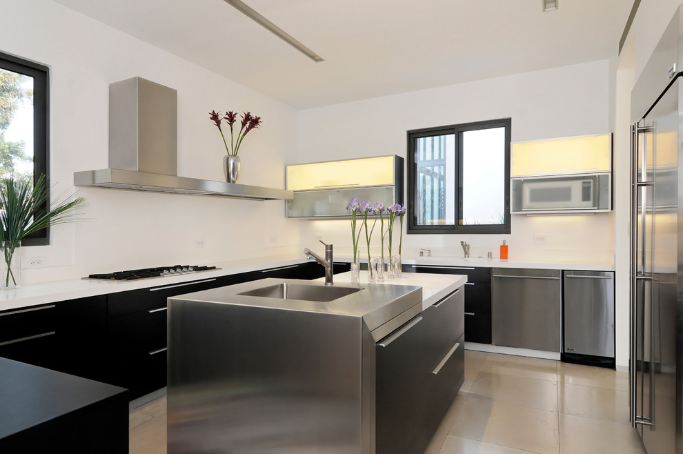 Immagine di una cucina ad U minimal con lavello integrato, ante lisce e elettrodomestici in acciaio inossidabile