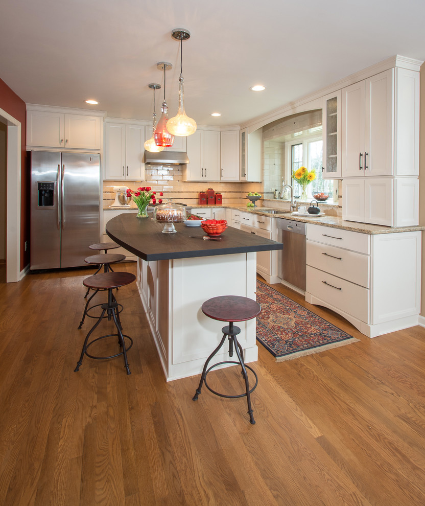 Inspiration for a huge timeless l-shaped medium tone wood floor open concept kitchen remodel in Columbus with an undermount sink, white cabinets, wood countertops, white backsplash, cement tile backsplash, stainless steel appliances, an island and recessed-panel cabinets