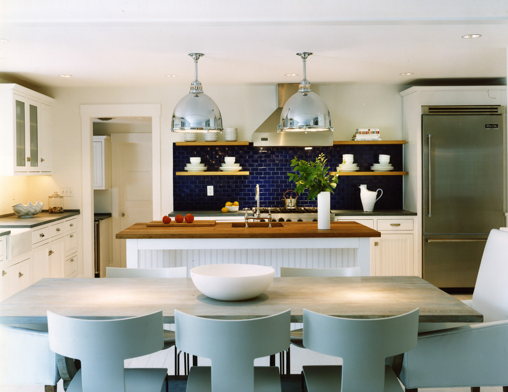 This is an example of a coastal galley kitchen/diner in DC Metro with metro tiled splashback, recessed-panel cabinets, white cabinets, granite worktops, blue splashback, stainless steel appliances, a belfast sink and an island.