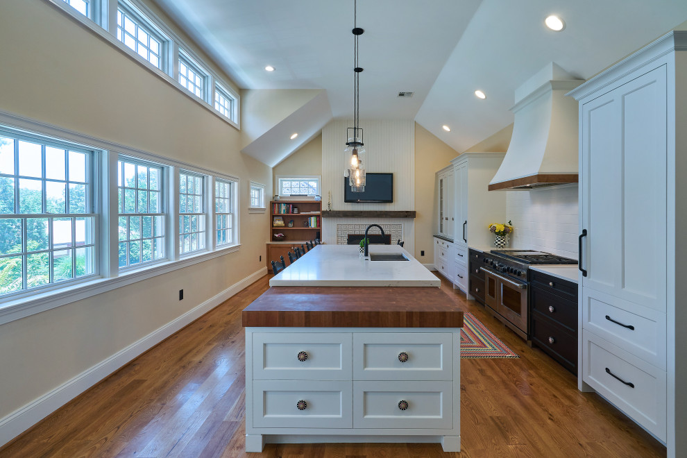Inspiration for a large farmhouse medium tone wood floor and brown floor kitchen remodel in Philadelphia with an undermount sink, shaker cabinets, white cabinets, quartz countertops, white backsplash, porcelain backsplash, paneled appliances, an island and white countertops