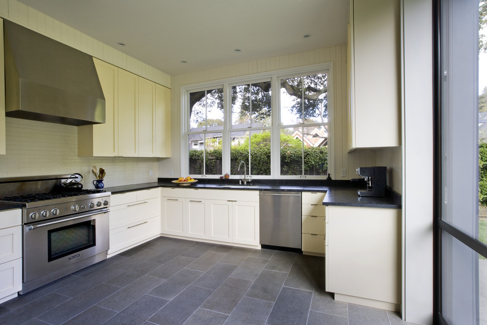 Immagine di una cucina ad U design con ante in stile shaker, ante beige, paraspruzzi beige, elettrodomestici in acciaio inossidabile e pavimento grigio