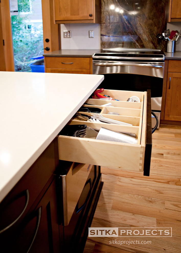 Example of a mid-sized classic u-shaped light wood floor enclosed kitchen design in Portland with an undermount sink, shaker cabinets, medium tone wood cabinets, beige backsplash, ceramic backsplash, stainless steel appliances and an island
