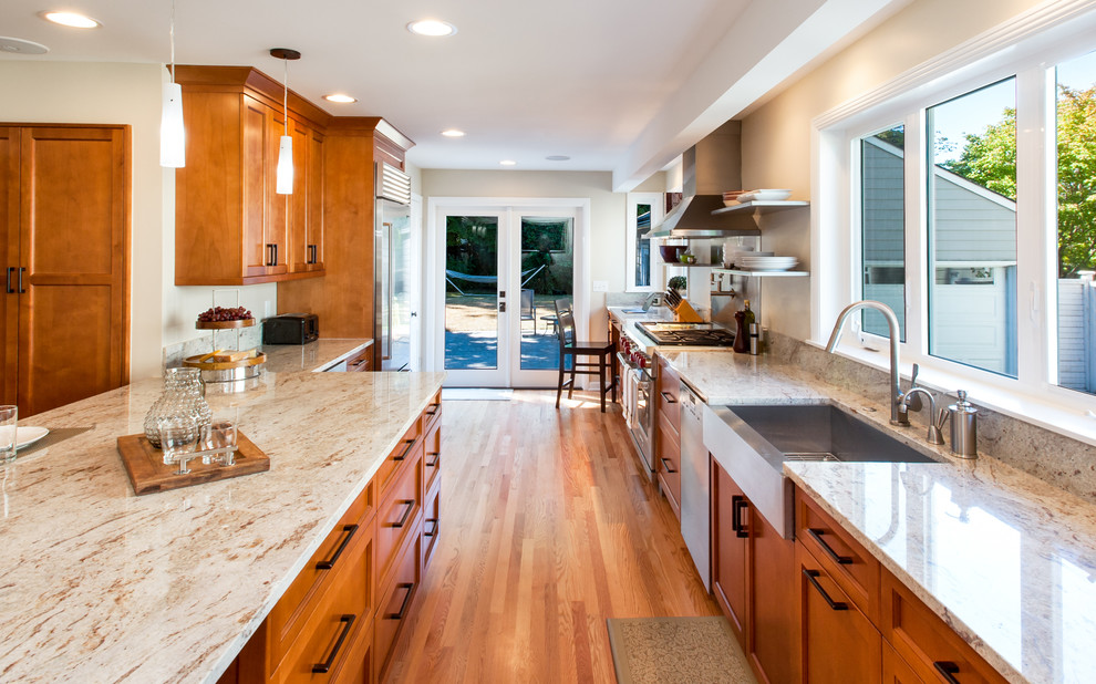 Cette photo montre une grande cuisine américaine craftsman en bois brun avec un évier encastré, plan de travail en marbre, un électroménager en acier inoxydable et un sol en bois brun.