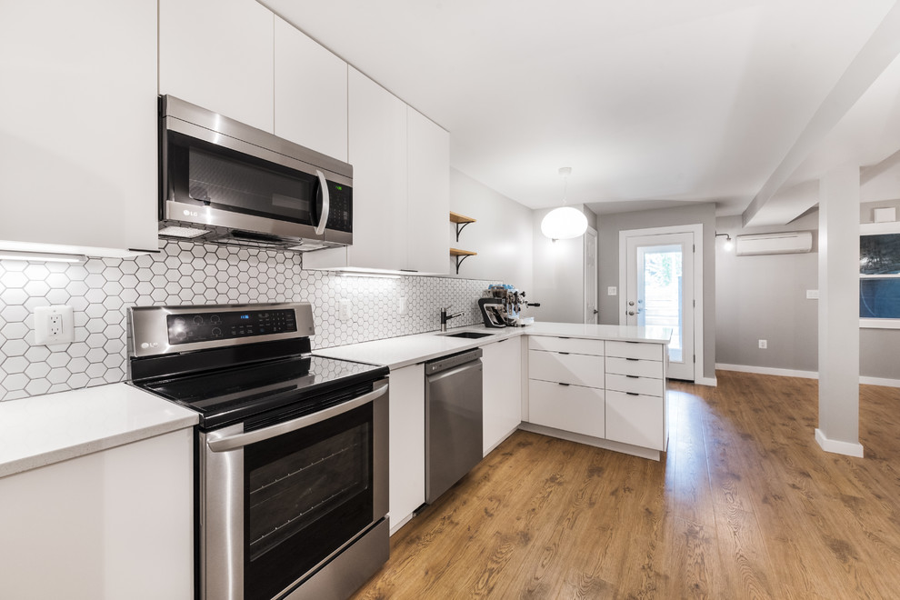 Medium sized modern l-shaped kitchen/diner in DC Metro with a single-bowl sink, shaker cabinets, white cabinets, composite countertops, white splashback, mosaic tiled splashback, stainless steel appliances, a breakfast bar and white worktops.
