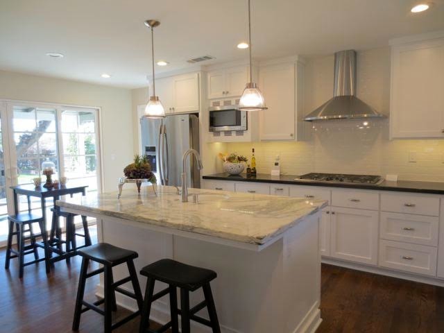 This is an example of a medium sized traditional u-shaped kitchen/diner in Sacramento with a belfast sink, shaker cabinets, white cabinets, marble worktops, white splashback, metro tiled splashback, stainless steel appliances, dark hardwood flooring, an island, brown floors and grey worktops.