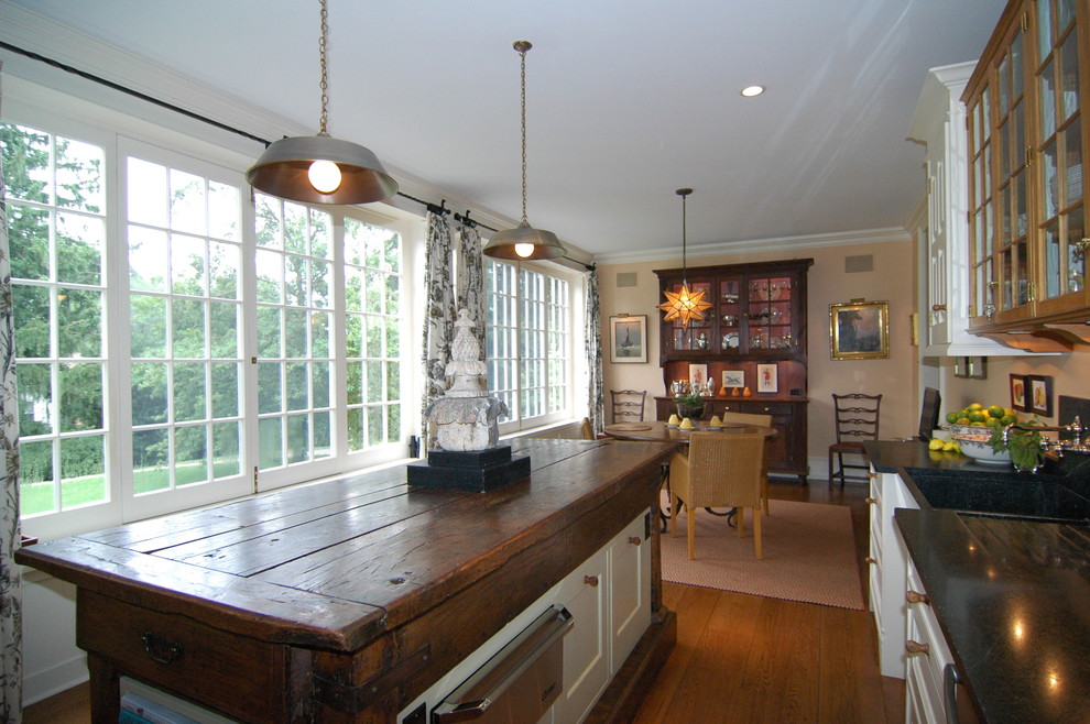 Inredning av ett lantligt stort kök och matrum, med en rustik diskho, luckor med glaspanel, granitbänkskiva, grått stänkskydd, rostfria vitvaror, mellanmörkt trägolv och en köksö