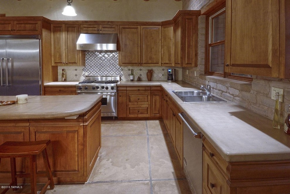 Foto på ett stort amerikanskt kök, med en nedsänkt diskho, luckor med upphöjd panel, bruna skåp, granitbänkskiva, beige stänkskydd, stänkskydd i keramik, rostfria vitvaror, klinkergolv i keramik och en köksö