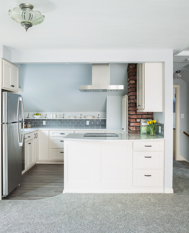 Idéer för att renovera ett litet funkis kök, med en undermonterad diskho, skåp i shakerstil, vita skåp, bänkskiva i kvartsit, grått stänkskydd, stänkskydd i glaskakel, rostfria vitvaror, vinylgolv och en halv köksö