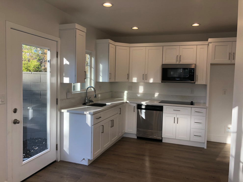 Photo of a medium sized classic l-shaped open plan kitchen in Los Angeles with a submerged sink, shaker cabinets, white cabinets, quartz worktops, beige splashback, stone slab splashback, stainless steel appliances, vinyl flooring, no island, brown floors, beige worktops and a drop ceiling.