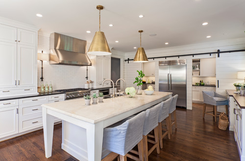 Spacious white kitchen with premium RTA cabinets Canada, large quartz island, brass pendants, and stainless range and fridge.