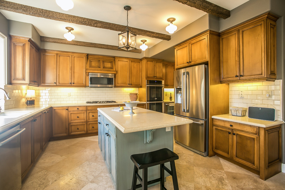 Inspiration for a mid-sized timeless u-shaped travertine floor eat-in kitchen remodel in Los Angeles with a double-bowl sink, raised-panel cabinets, medium tone wood cabinets, quartz countertops, beige backsplash, ceramic backsplash, stainless steel appliances and an island