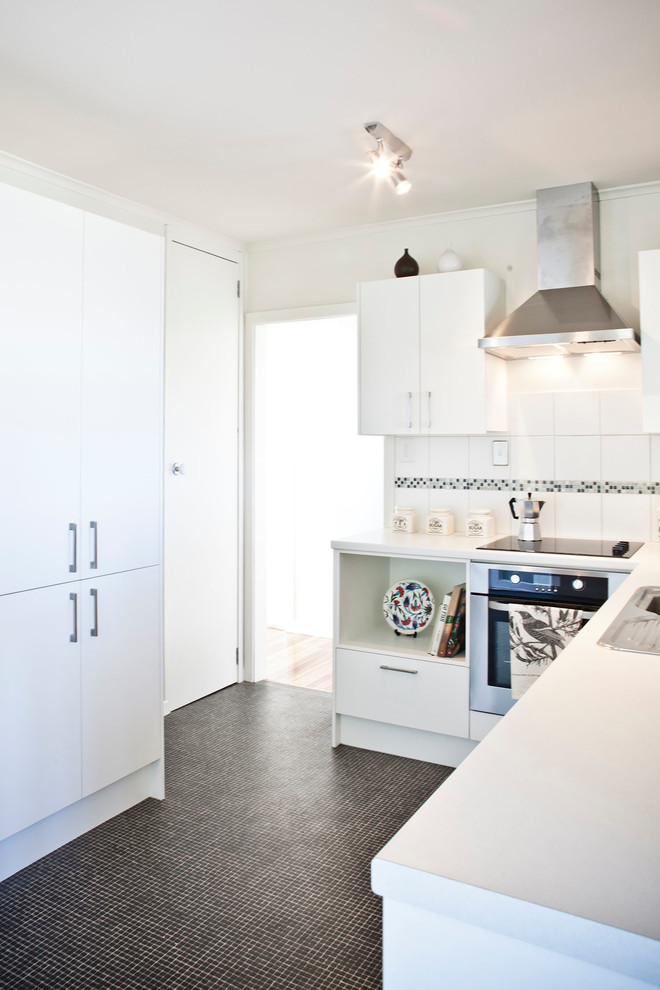 Inspiration for a small contemporary l-shaped vinyl floor and multicolored floor eat-in kitchen remodel in Auckland with a single-bowl sink, flat-panel cabinets, white cabinets, laminate countertops, white backsplash, ceramic backsplash, stainless steel appliances and no island