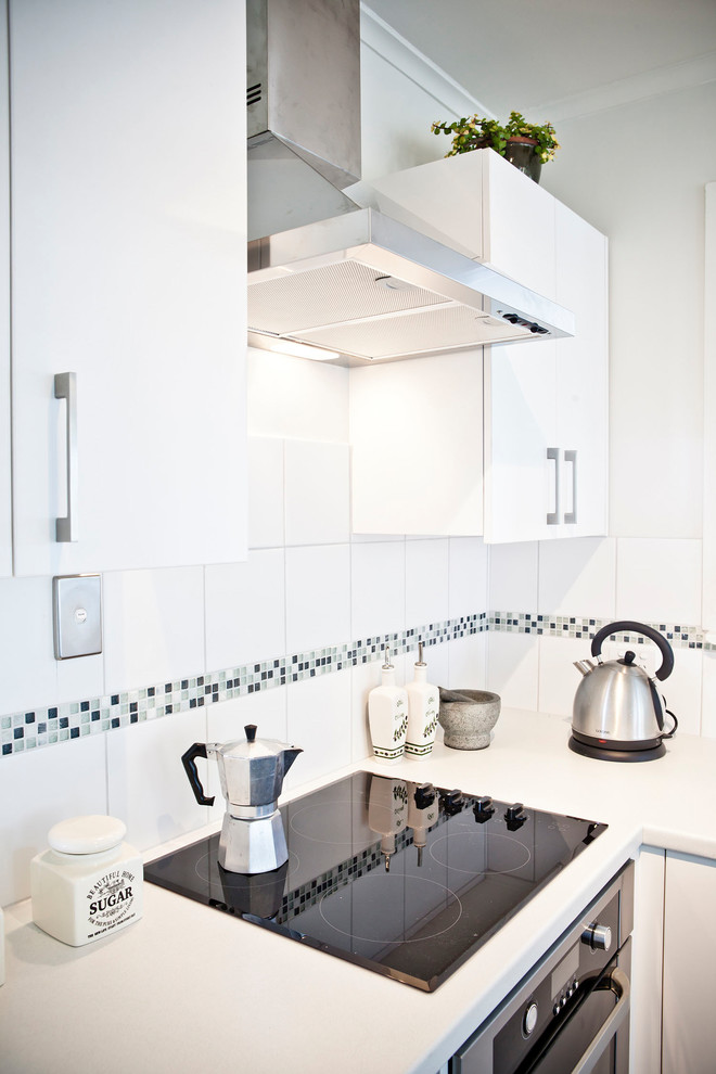 Idéer för att renovera ett litet funkis kök, med en enkel diskho, släta luckor, vita skåp, laminatbänkskiva, vitt stänkskydd, stänkskydd i keramik, rostfria vitvaror, vinylgolv och flerfärgat golv