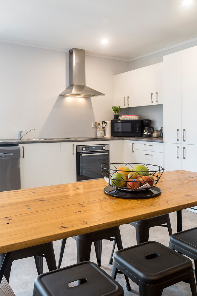 Mid-sized minimalist l-shaped linoleum floor and multicolored floor open concept kitchen photo in Auckland with a drop-in sink, flat-panel cabinets, white cabinets, solid surface countertops, stainless steel appliances, no island and multicolored countertops