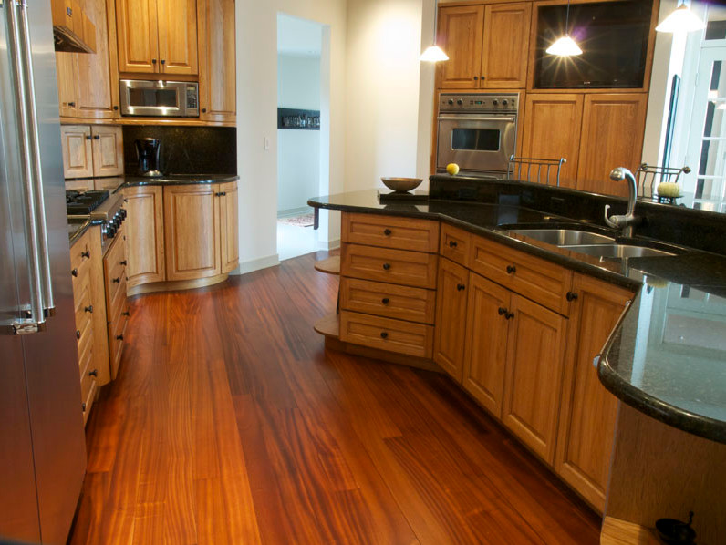 Idéer för att renovera ett avskilt, stort vintage linjärt kök, med en dubbel diskho, luckor med upphöjd panel, skåp i mellenmörkt trä, bänkskiva i kvarts, svart stänkskydd, rostfria vitvaror, mellanmörkt trägolv, en köksö och brunt golv