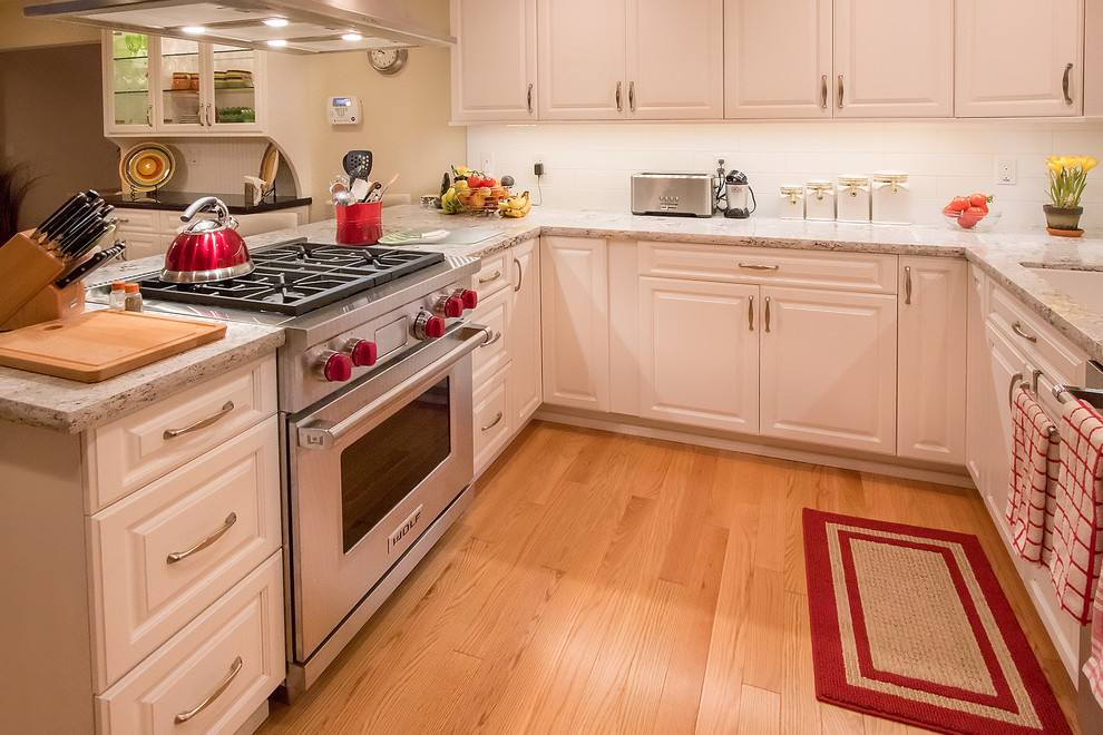 サンフランシスコにある高級な中くらいなトラディショナルスタイルのおしゃれなキッチン (アンダーカウンターシンク、レイズドパネル扉のキャビネット、白いキャビネット、クオーツストーンカウンター、白いキッチンパネル、サブウェイタイルのキッチンパネル、シルバーの調理設備、淡色無垢フローリング) の写真