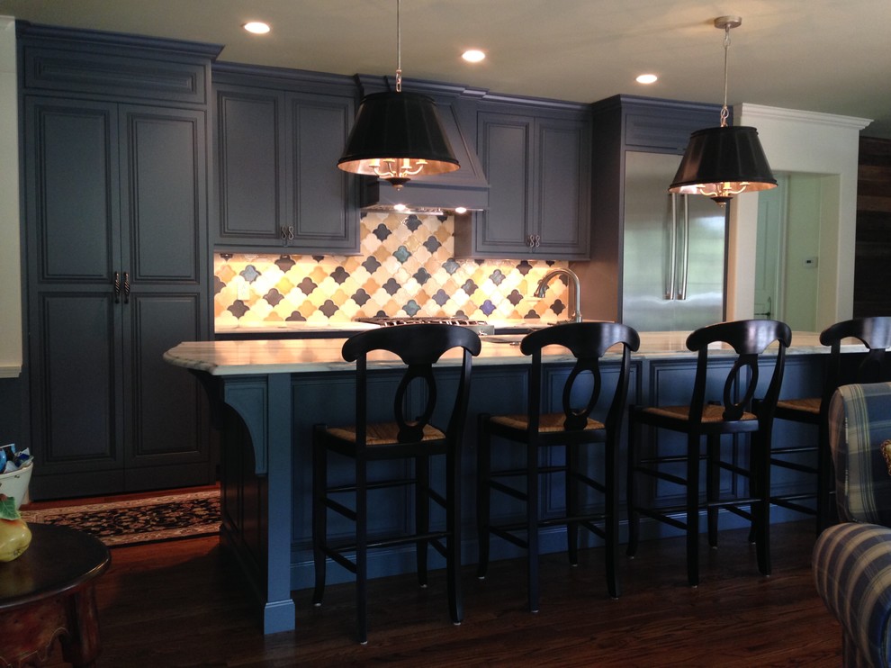 Inredning av ett klassiskt mellanstort linjärt kök, med en dubbel diskho, luckor med profilerade fronter, blå skåp, marmorbänkskiva, gult stänkskydd, stänkskydd i keramik, rostfria vitvaror, mellanmörkt trägolv och en köksö
