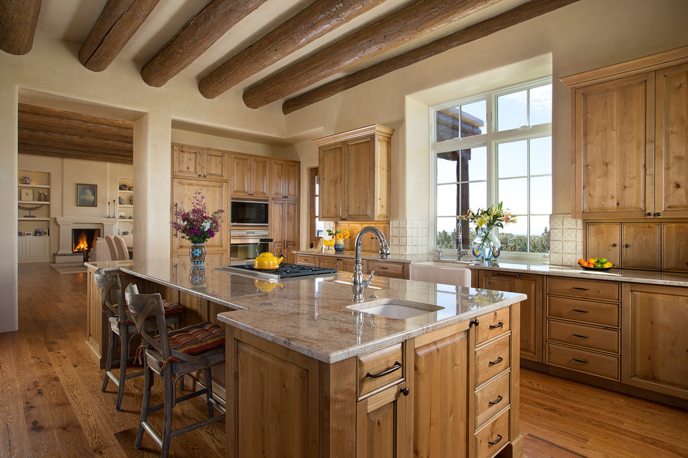 Réalisation d'une cuisine méditerranéenne en bois brun et L fermée et de taille moyenne avec un évier de ferme, un placard avec porte à panneau surélevé, une crédence blanche, un sol en bois brun, îlot, un plan de travail en granite, une crédence en céramique et un électroménager en acier inoxydable.