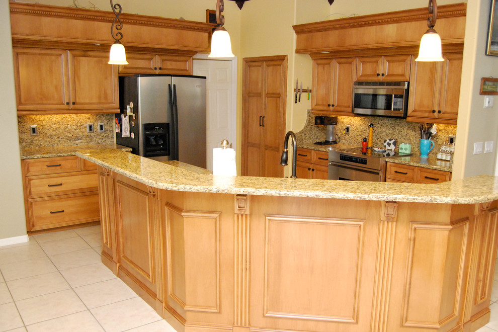This is an example of a medium sized classic u-shaped kitchen/diner in Miami with a submerged sink, raised-panel cabinets, light wood cabinets, granite worktops, beige splashback, stone slab splashback, stainless steel appliances, ceramic flooring, an island and beige floors.