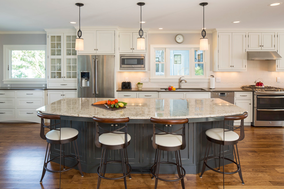 Inspiration for a large timeless single-wall medium tone wood floor and brown floor eat-in kitchen remodel in Minneapolis with an undermount sink, recessed-panel cabinets, white cabinets, granite countertops, white backsplash, subway tile backsplash, stainless steel appliances and an island