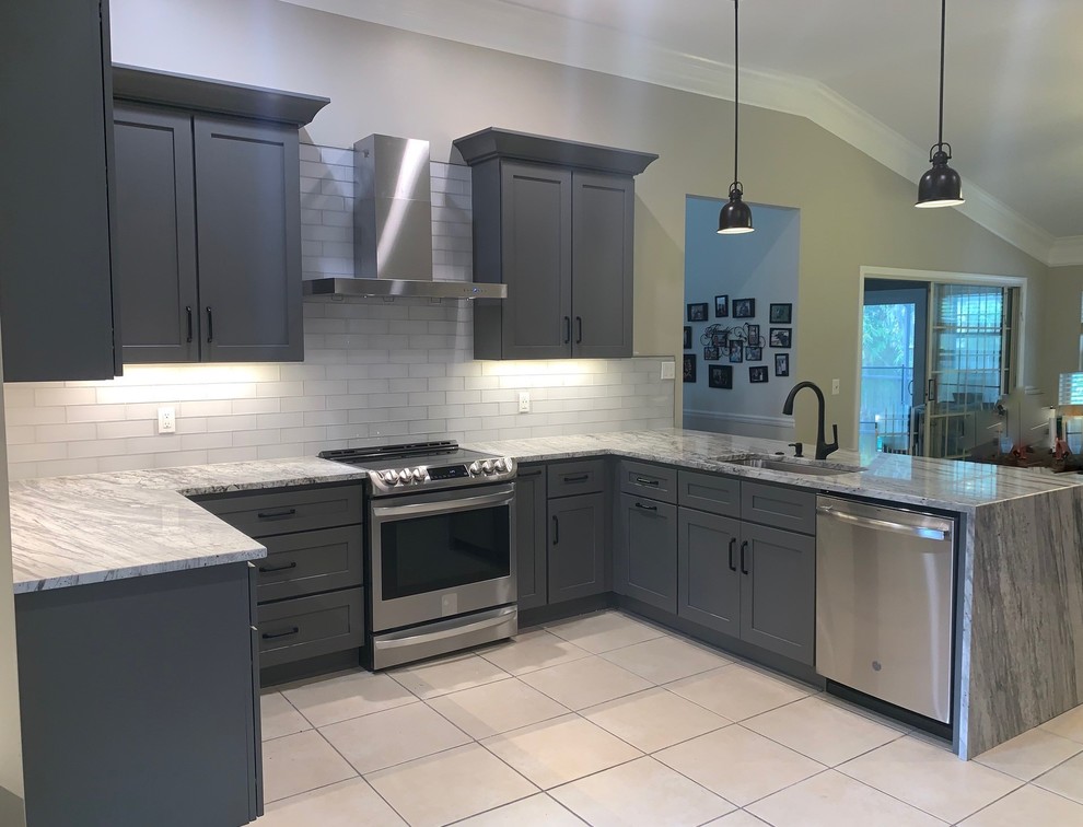 Idéer för att renovera ett mellanstort vintage grå grått kök, med en enkel diskho, skåp i shakerstil, grå skåp, granitbänkskiva, vitt stänkskydd, stänkskydd i tunnelbanekakel, rostfria vitvaror, klinkergolv i keramik, en halv köksö och beiget golv