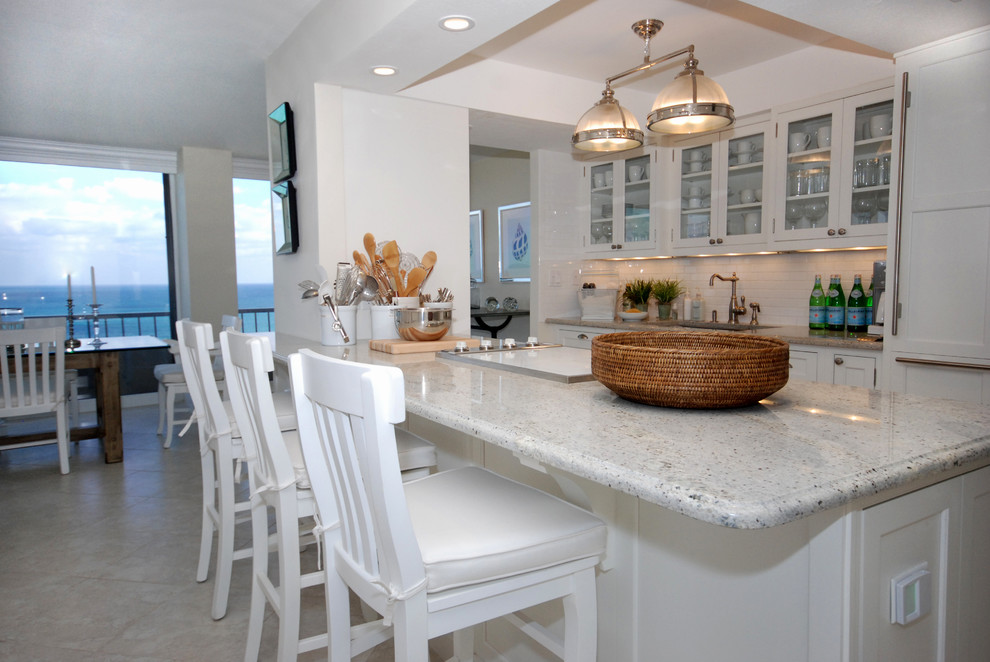 Inspiration for a beach style galley open plan kitchen in Miami with shaker cabinets, white cabinets, white splashback, ceramic splashback and travertine flooring.