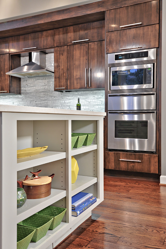 Mid-sized trendy single-wall medium tone wood floor open concept kitchen photo in Austin with an undermount sink, flat-panel cabinets, dark wood cabinets, quartz countertops, gray backsplash and stainless steel appliances