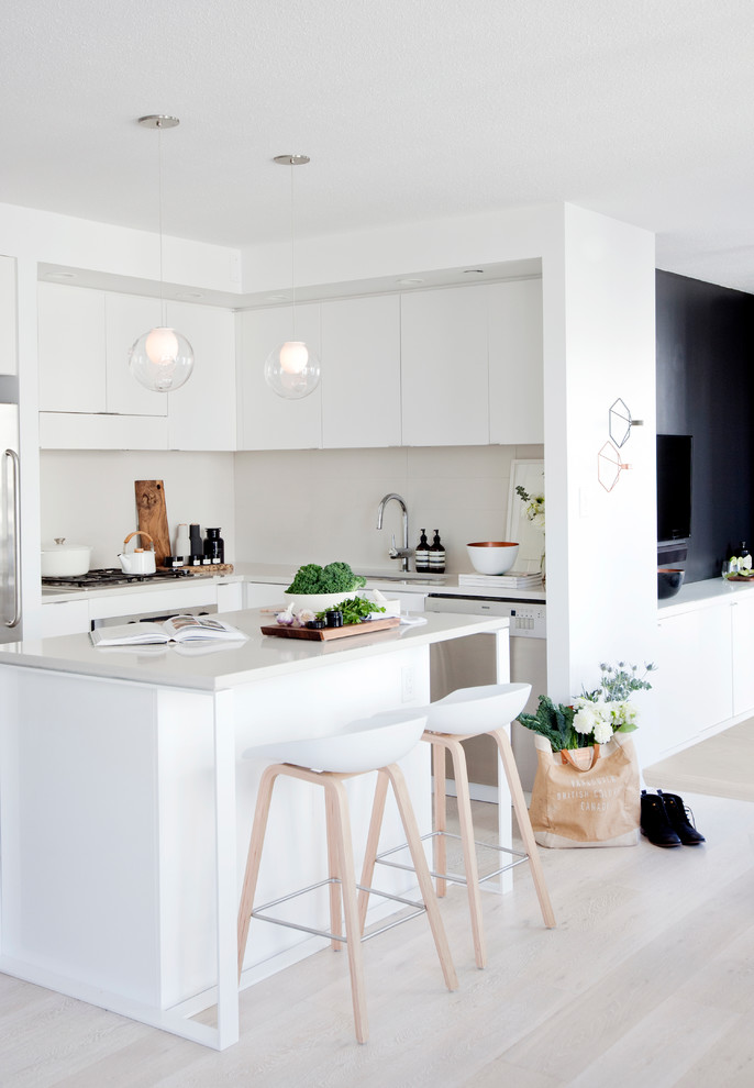 Exempel på ett litet minimalistiskt kök, med en undermonterad diskho, släta luckor, vita skåp, bänkskiva i kvarts, rostfria vitvaror, ljust trägolv och en köksö