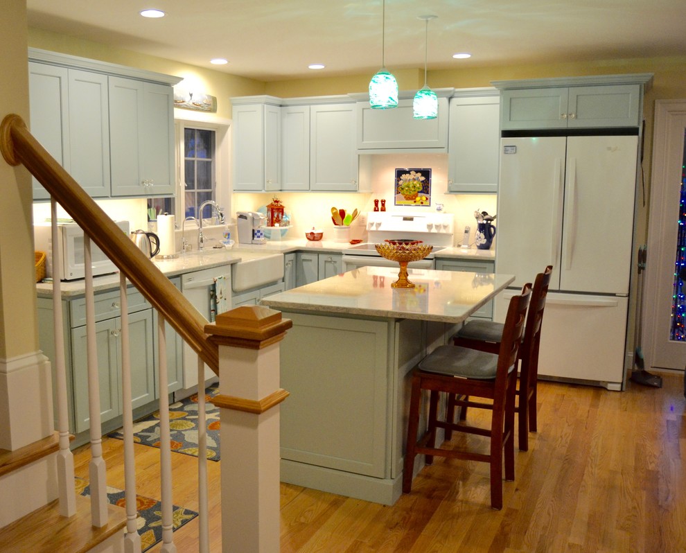 Example of a mid-sized beach style l-shaped medium tone wood floor eat-in kitchen design in Boston with a farmhouse sink, flat-panel cabinets, turquoise cabinets, quartz countertops, white backsplash, subway tile backsplash, white appliances and an island