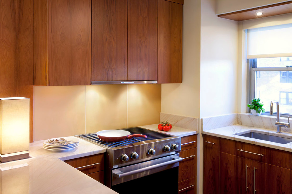 Bild på ett avskilt, mellanstort funkis l-kök, med en undermonterad diskho, släta luckor, beige stänkskydd, skåp i mellenmörkt trä, bänkskiva i kvarts, integrerade vitvaror, mörkt trägolv och en köksö