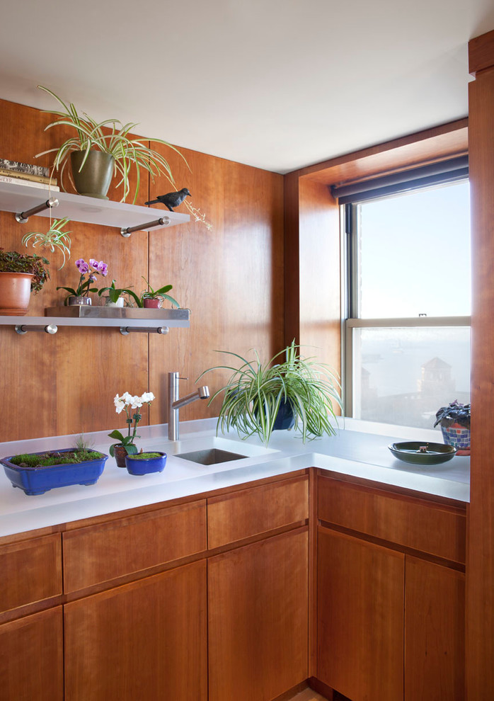 Immagine di una piccola cucina a L minimalista chiusa con lavello sottopiano, ante lisce, ante in legno scuro, top in vetro e nessuna isola