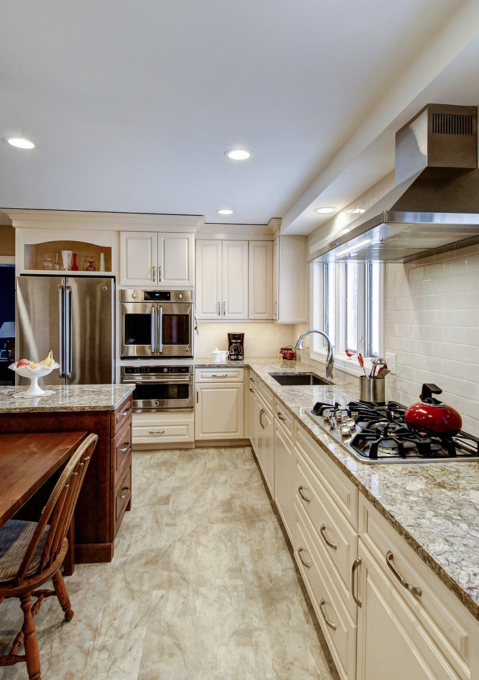 Inspiration for a mid-sized transitional l-shaped vinyl floor and brown floor eat-in kitchen remodel in Philadelphia with an undermount sink, raised-panel cabinets, white cabinets, granite countertops, white backsplash, ceramic backsplash, stainless steel appliances, an island and gray countertops