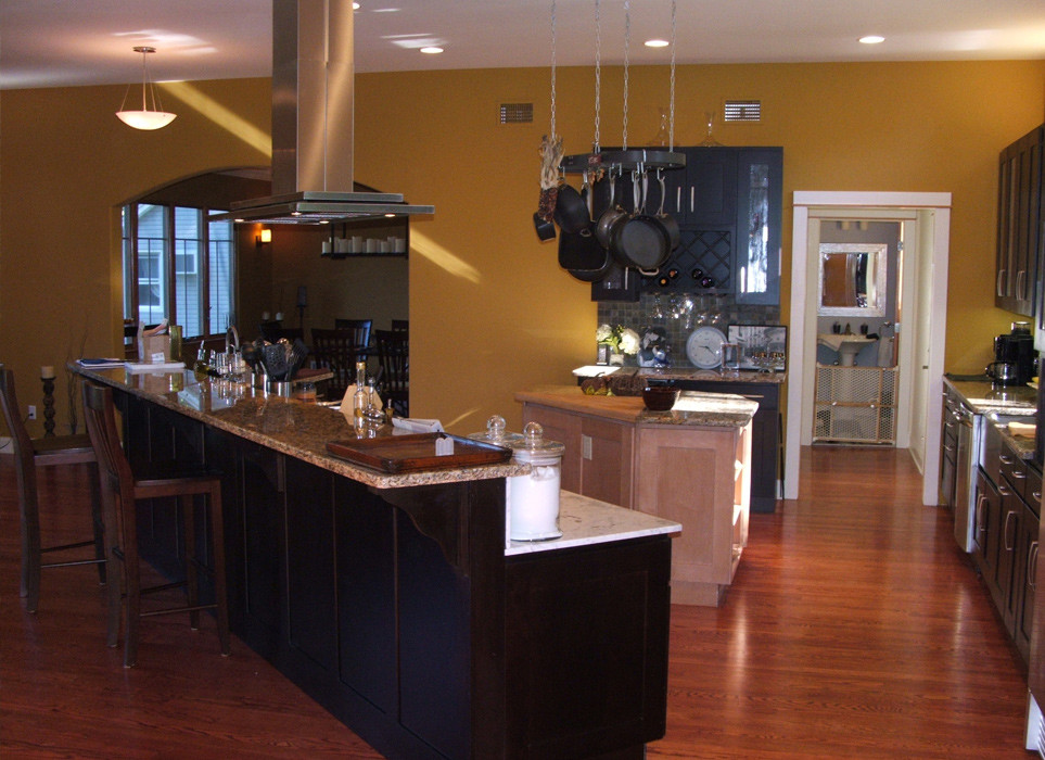 Eklektisk inredning av ett stort kök med öppen planlösning, med en undermonterad diskho, luckor med infälld panel, svarta skåp, granitbänkskiva, grönt stänkskydd, stänkskydd i stenkakel, rostfria vitvaror, mellanmörkt trägolv och flera köksöar