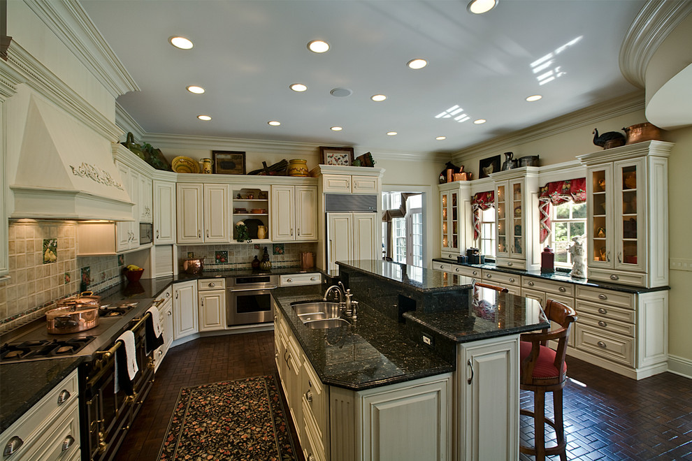 Bild på ett stort vintage u-kök, med luckor med upphöjd panel, vita skåp, granitbänkskiva, mörkt trägolv, en köksö, en dubbel diskho, grått stänkskydd, stänkskydd i keramik, rostfria vitvaror och brunt golv