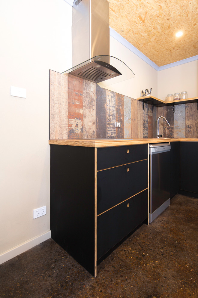 Diseño de cocina urbana pequeña con fregadero encastrado, armarios con paneles lisos, puertas de armario negras, encimera de madera y suelo de cemento