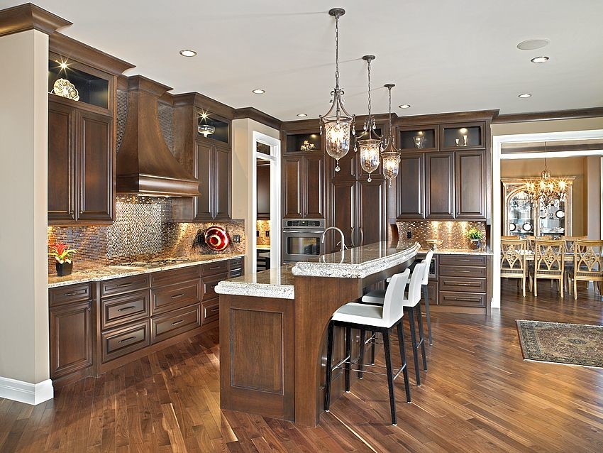 Trendy l-shaped enclosed kitchen photo in Calgary with an integrated sink, raised-panel cabinets, dark wood cabinets, granite countertops, brown backsplash and paneled appliances