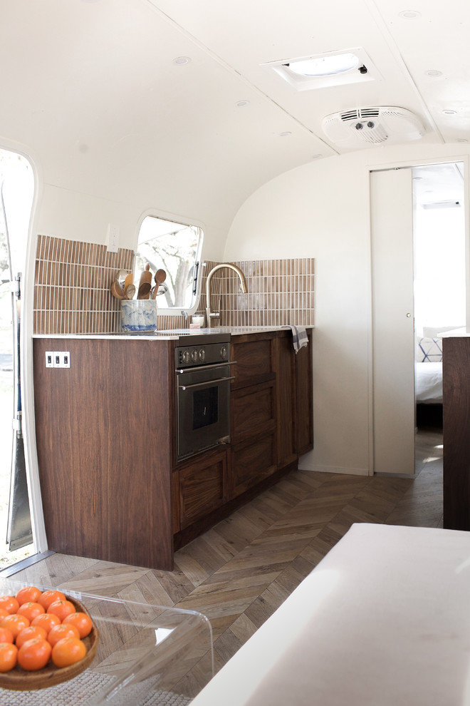 Foto på ett litet 50 tals kök, med brunt stänkskydd, stänkskydd i keramik, mellanmörkt trägolv och brunt golv