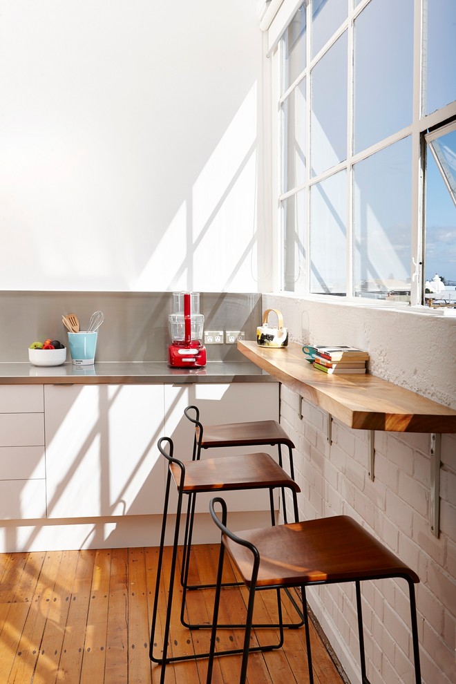 Eat-in kitchen - mid-sized contemporary single-wall medium tone wood floor eat-in kitchen idea in Auckland with white cabinets, no island, a double-bowl sink, stainless steel countertops, stainless steel appliances and gray countertops
