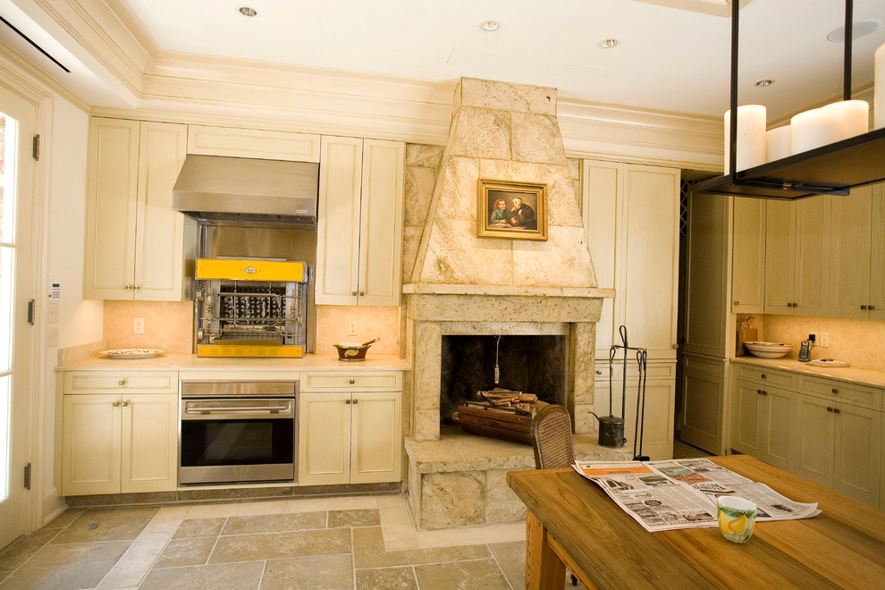 Diseño de cocina clásica con armarios con paneles empotrados, puertas de armario beige, salpicadero beige y electrodomésticos de acero inoxidable