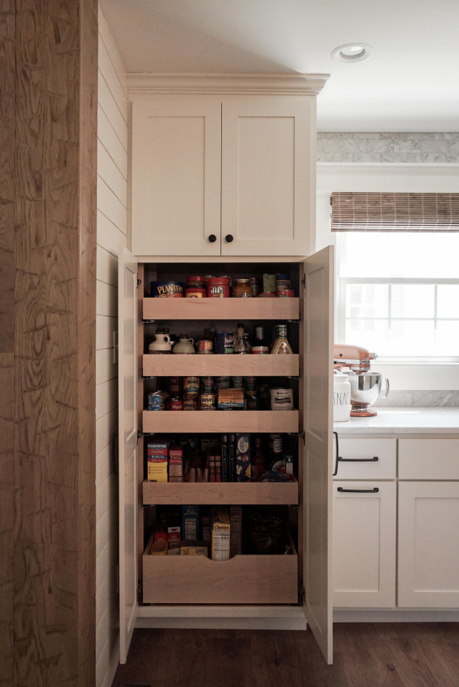 Bild på ett mellanstort lantligt vit vitt kök, med en undermonterad diskho, skåp i shakerstil, vita skåp, bänkskiva i kvarts, grått stänkskydd, stänkskydd i marmor, rostfria vitvaror, mellanmörkt trägolv, en köksö och brunt golv