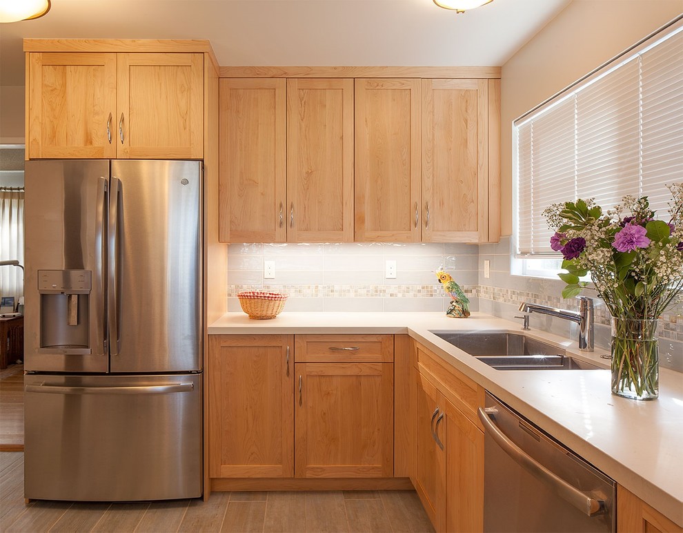 Idée de décoration pour une grande cuisine tradition en L et bois clair fermée avec un évier encastré, un placard à porte shaker, un plan de travail en quartz modifié, une crédence bleue, une crédence en céramique, un électroménager en acier inoxydable, un sol en carrelage de porcelaine, aucun îlot, un sol bleu et un plan de travail blanc.