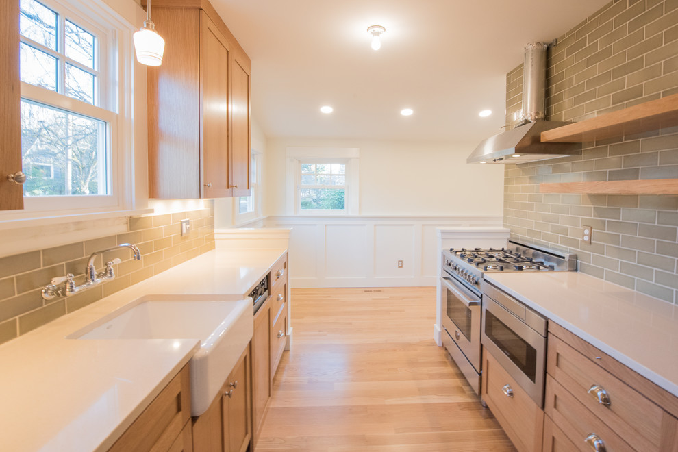 Example of a small arts and crafts galley medium tone wood floor eat-in kitchen design in Portland with a farmhouse sink, shaker cabinets, medium tone wood cabinets, quartz countertops, green backsplash, ceramic backsplash and stainless steel appliances