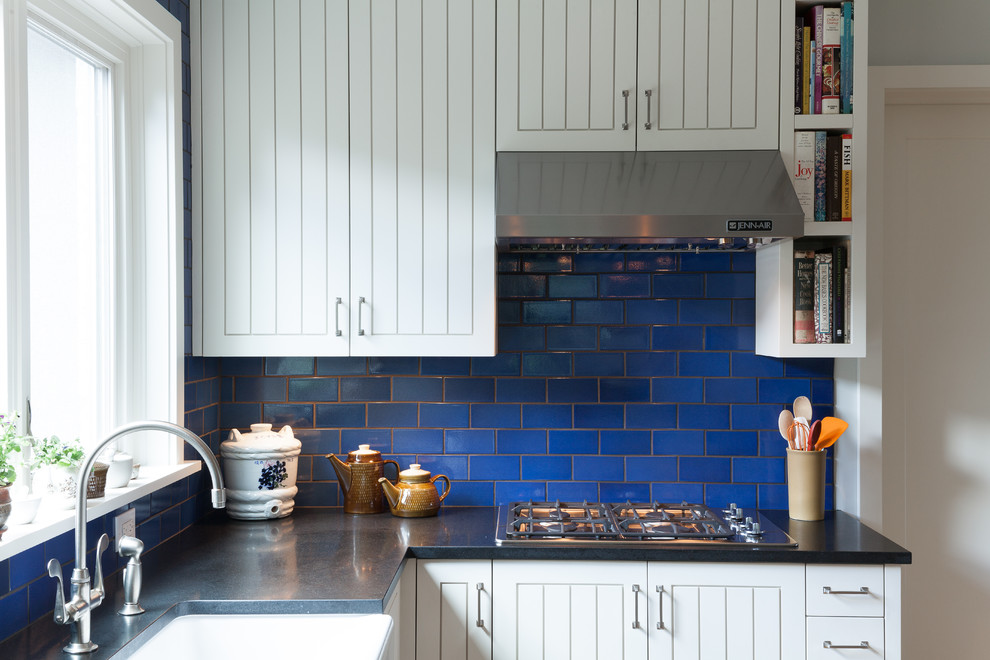 Moderne Wohnküche in U-Form mit Küchengeräten aus Edelstahl, Landhausspüle, weißen Schränken, Granit-Arbeitsplatte, Küchenrückwand in Blau, Rückwand aus Metrofliesen und Schrankfronten mit vertiefter Füllung in Portland