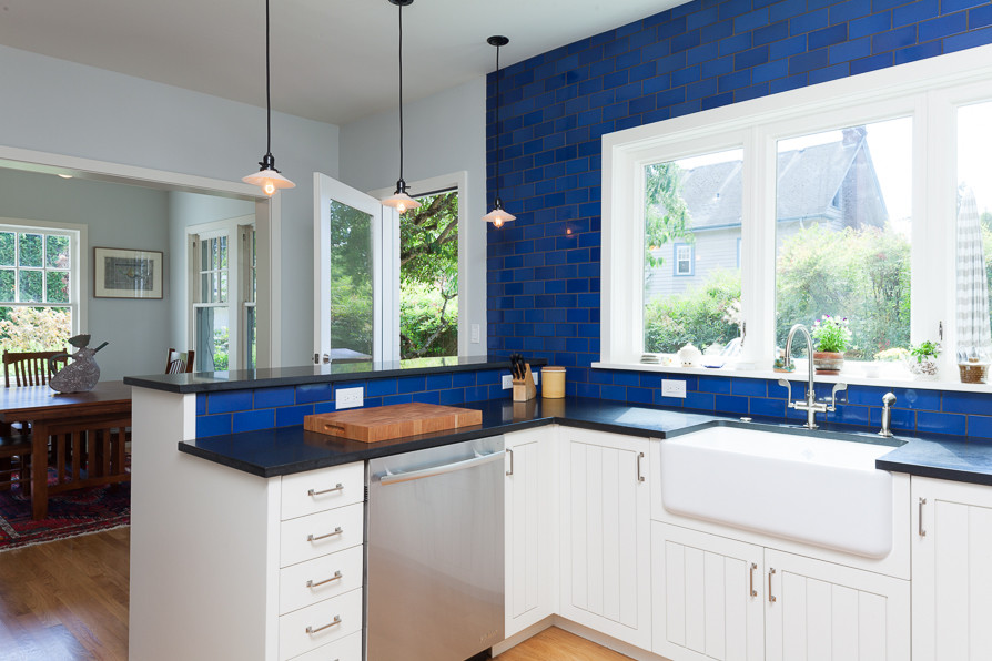 Photo of a traditional u-shaped kitchen/diner in Portland with a belfast sink, beaded cabinets, white cabinets, granite worktops, blue splashback, ceramic splashback and stainless steel appliances.