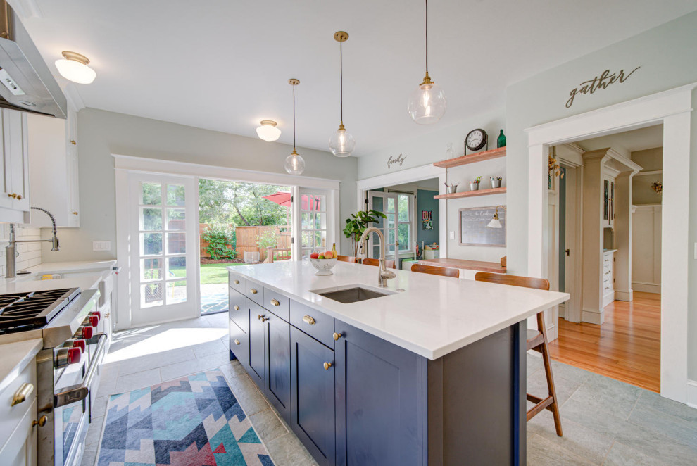 Example of a mid-sized transitional ceramic tile and gray floor kitchen design in Portland with a farmhouse sink, shaker cabinets, quartz countertops, white backsplash, ceramic backsplash, stainless steel appliances, an island and white countertops