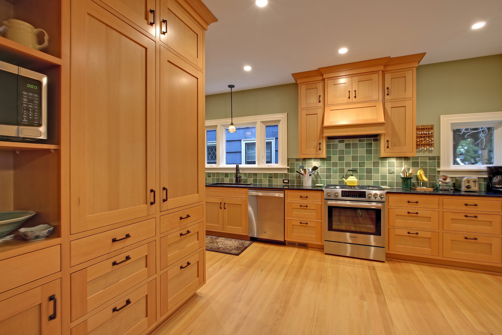 Exempel på ett mellanstort amerikanskt kök, med en undermonterad diskho, skåp i shakerstil, skåp i ljust trä, granitbänkskiva, grönt stänkskydd, stänkskydd i keramik, rostfria vitvaror och ljust trägolv