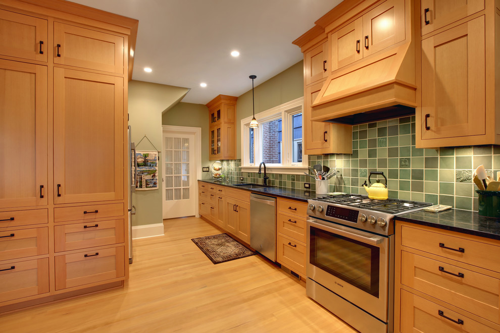 Amerikansk inredning av ett mellanstort kök, med en undermonterad diskho, skåp i shakerstil, skåp i ljust trä, granitbänkskiva, grönt stänkskydd, stänkskydd i keramik, rostfria vitvaror och ljust trägolv