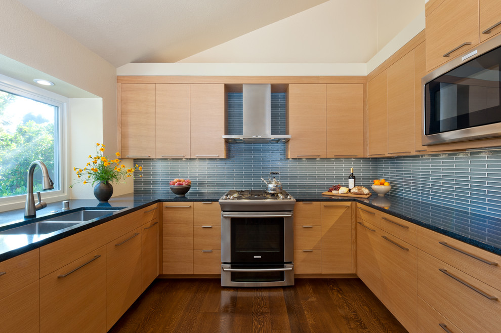 Источник вдохновения для домашнего уюта: п-образная кухня в современном стиле с двойной мойкой, плоскими фасадами, светлыми деревянными фасадами и синим фартуком