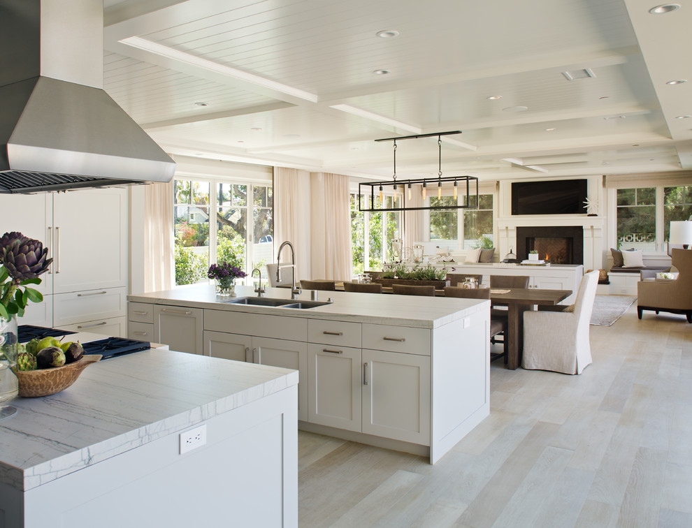 Example of a large transitional galley light wood floor and beige floor open concept kitchen design in San Diego with a drop-in sink, beaded inset cabinets, white cabinets, stainless steel appliances, two islands and marble countertops