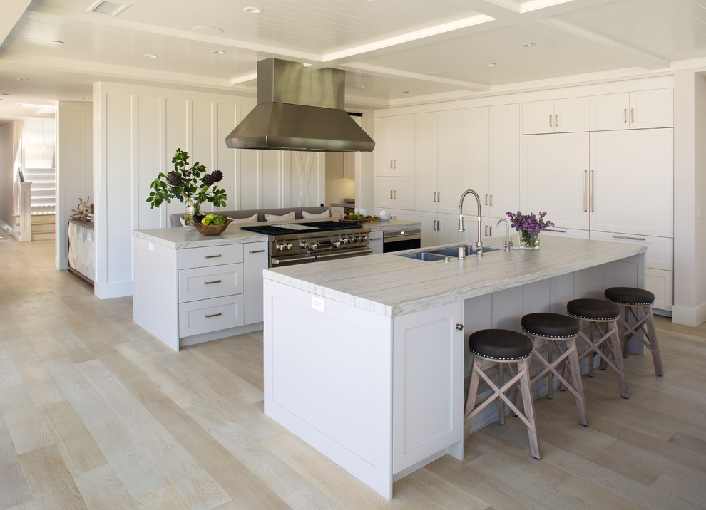 サンディエゴにある広いトランジショナルスタイルのおしゃれなキッチン (ダブルシンク、シェーカースタイル扉のキャビネット、白いキャビネット、大理石カウンター、シルバーの調理設備、淡色無垢フローリング、ベージュの床) の写真